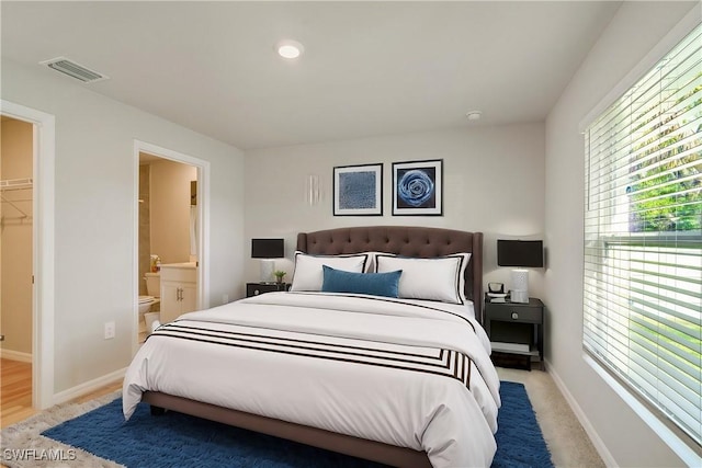 bedroom featuring connected bathroom, baseboards, multiple windows, and visible vents