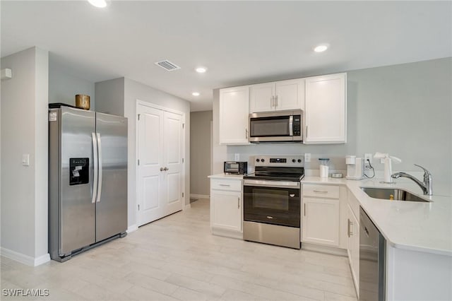 kitchen featuring light countertops, a sink, visible vents, white cabinets, and appliances with stainless steel finishes