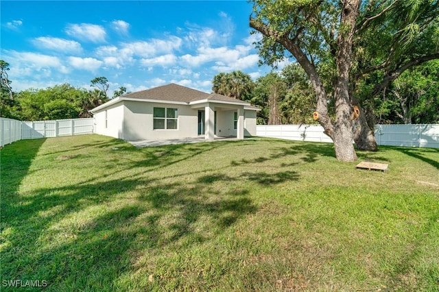 back of property with a fenced backyard, stucco siding, and a lawn