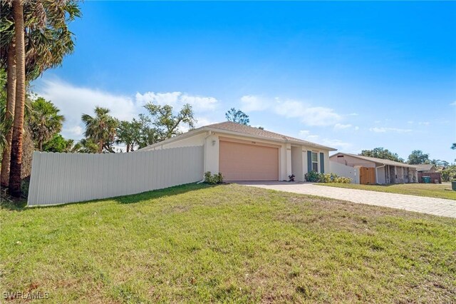 view of front of house featuring driveway, stucco siding, fence, and a front lawn