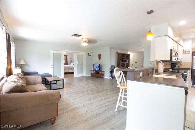 77 Cardinal Dr, North Fort Myers, FL 33917 - kitchen with open floor plan, a sink, a kitchen breakfast bar, and white cabinetry