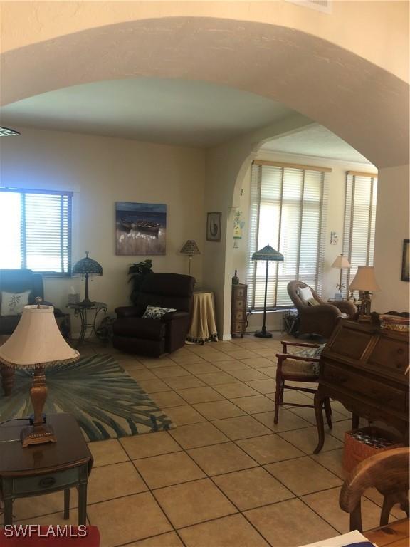 living area with arched walkways and light tile patterned floors