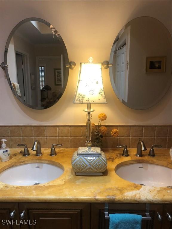 bathroom with decorative backsplash, a sink, and double vanity
