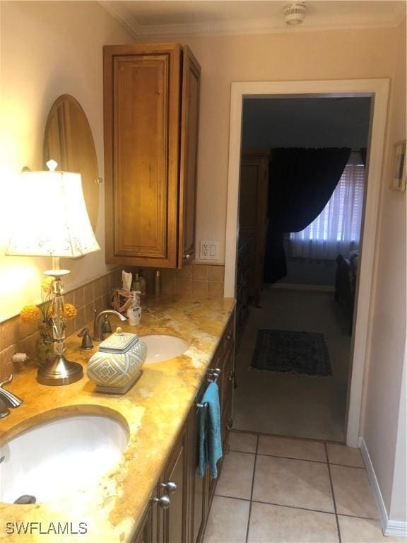 bathroom featuring tile patterned flooring, double vanity, crown molding, and a sink