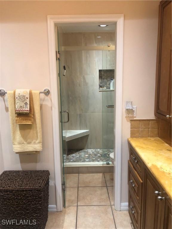 full bath with vanity, toilet, tile patterned flooring, and a stall shower