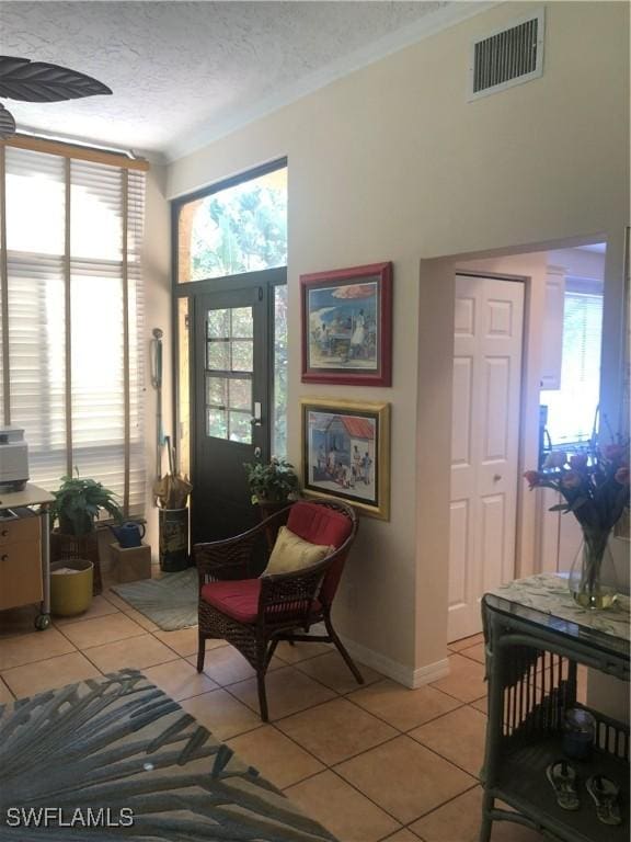 sitting room featuring a textured ceiling, plenty of natural light, visible vents, and light tile patterned floors