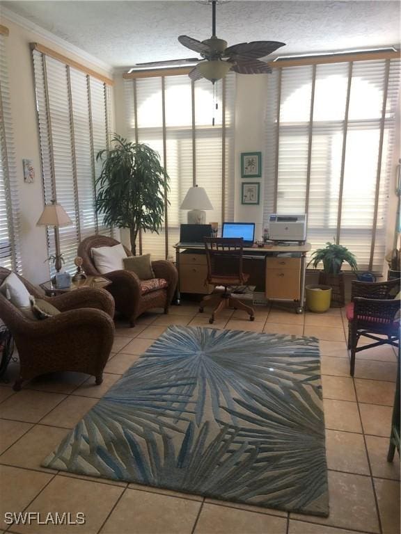 living area featuring a wealth of natural light, a ceiling fan, tile patterned flooring, and crown molding