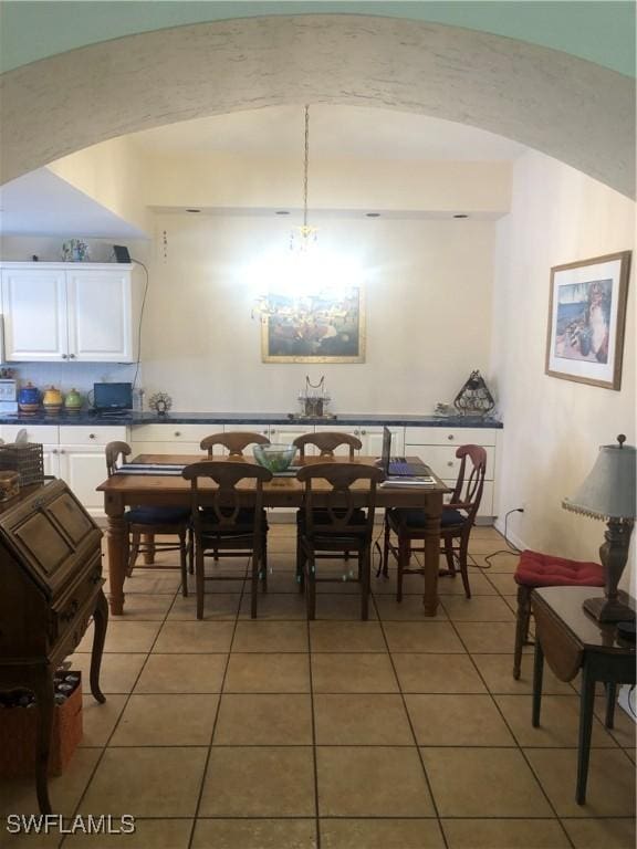 dining room featuring arched walkways and light tile patterned floors