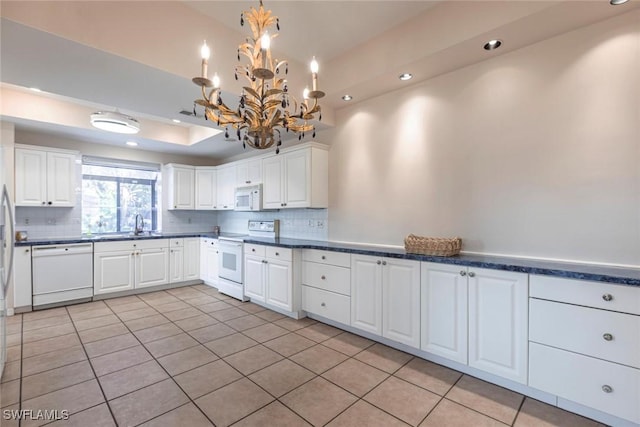 kitchen with decorative backsplash, an inviting chandelier, white appliances, and recessed lighting