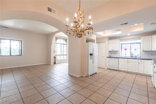 kitchen featuring arched walkways, visible vents, white appliances, and light tile patterned floors