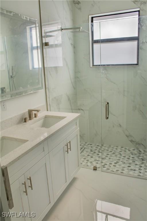 3202 72nd St W, Lehigh Acres, FL 33971 - bathroom featuring healthy amount of natural light, a marble finish shower, double vanity, and marble finish floors