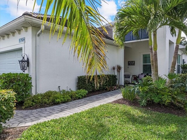 7024 Mistral Way, Fort Myers, FL 33966 - entrance to property with stucco siding, a garage, and a yard