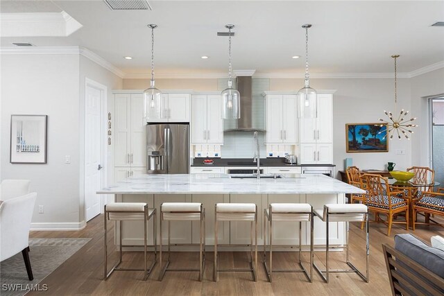 1002 Fountain Run, Naples, FL 34119 - kitchen featuring stainless steel refrigerator with ice dispenser, wall chimney range hood, a spacious island, a breakfast bar area, and recessed lighting