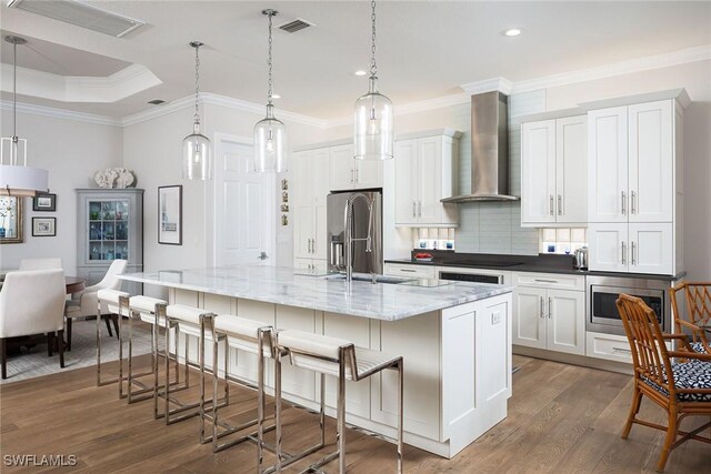 1002 Fountain Run, Naples, FL 34119 - kitchen featuring wall chimney range hood, stainless steel appliances, dark wood-type flooring, tasteful backsplash, and ornamental molding