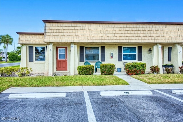 120 Gledhill Ct, Fort Myers, FL 33919 - view of front facade with uncovered parking, mansard roof, stucco siding, and a front yard