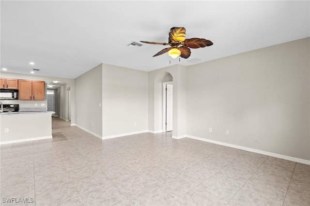 unfurnished living room with arched walkways, baseboards, ceiling fan, and visible vents