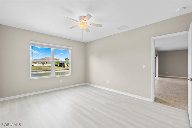 spare room featuring light wood-type flooring, baseboards, and ceiling fan