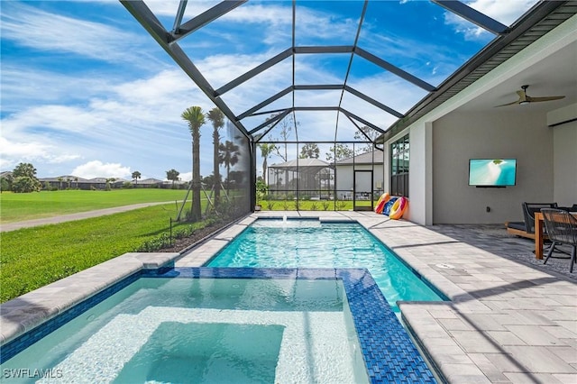 view of swimming pool with a patio area, ceiling fan, a pool with connected hot tub, a lawn, and a lanai