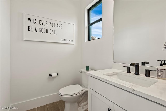 bathroom featuring toilet, wood finished floors, vanity, and baseboards