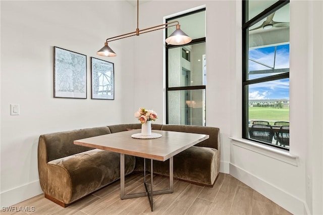 dining area featuring wood tiled floor, baseboards, and breakfast area