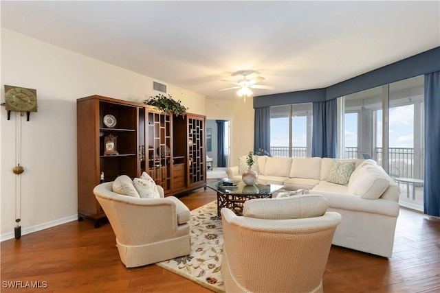 living area with visible vents, ceiling fan, wood finished floors, and baseboards
