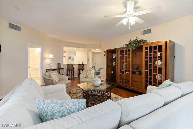living area featuring visible vents, a ceiling fan, and wood finished floors