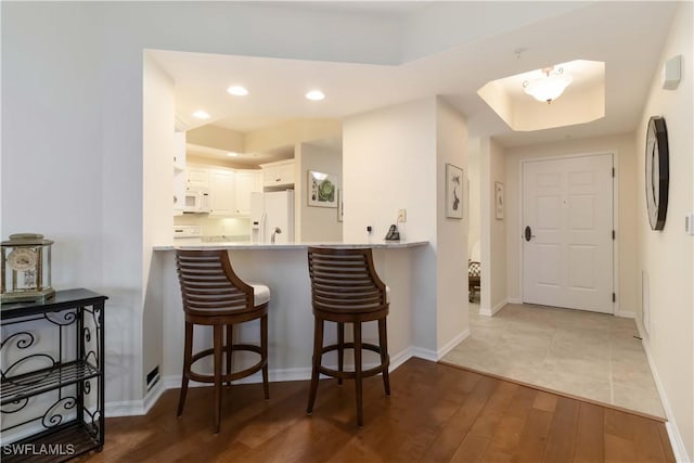 bar featuring recessed lighting, white appliances, hardwood / wood-style flooring, and baseboards