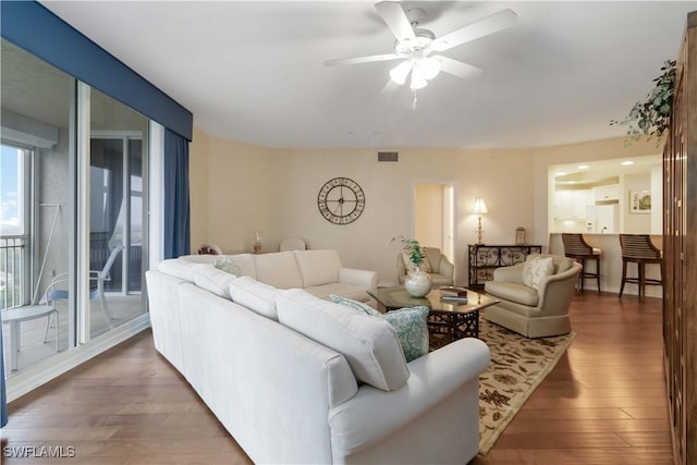 living area featuring wood-type flooring, a ceiling fan, and visible vents