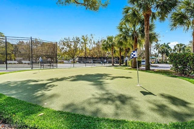 view of home's community with a tennis court and fence