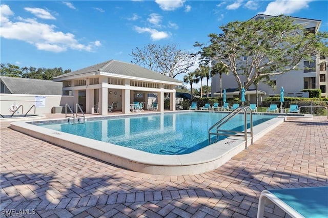 community pool featuring an outdoor structure, fence, and a patio
