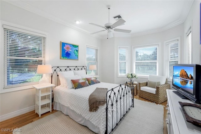 bedroom featuring visible vents, baseboards, a ceiling fan, wood finished floors, and crown molding