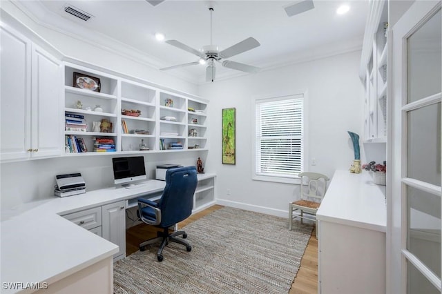 home office featuring a ceiling fan, built in desk, light wood-style floors, baseboards, and visible vents