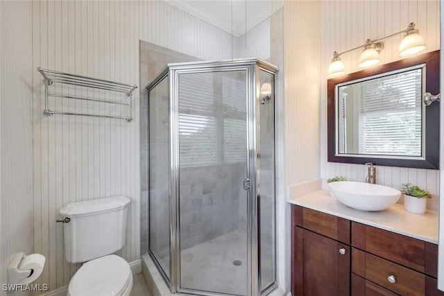 bathroom featuring toilet, vanity, ornamental molding, and a stall shower
