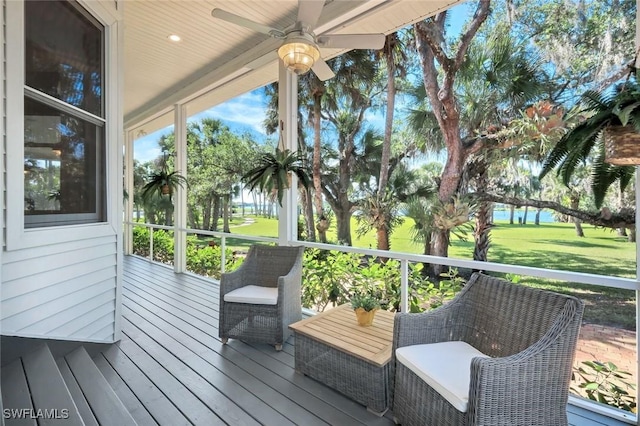 wooden deck with a lawn and ceiling fan