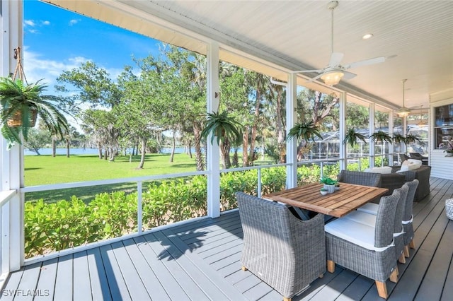 sunroom / solarium featuring a water view and a ceiling fan