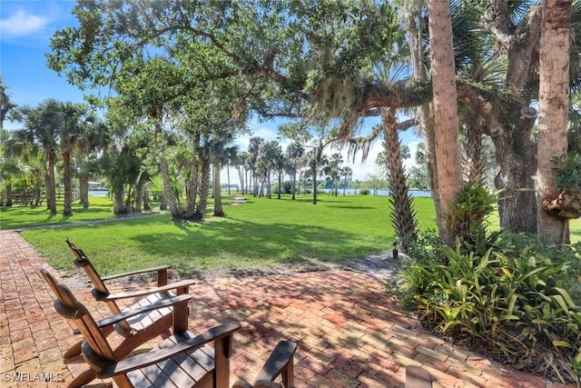 surrounding community featuring a yard, a patio area, and a water view