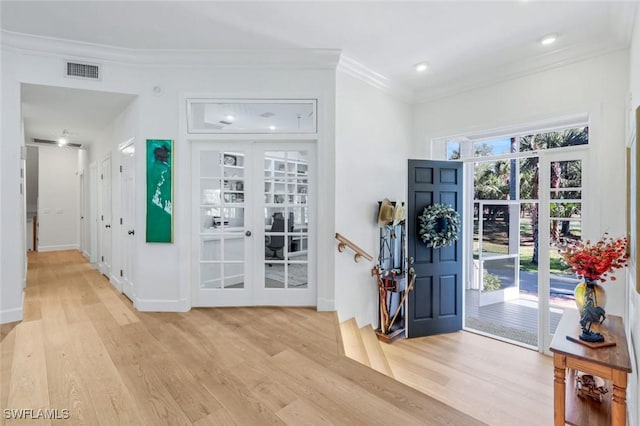 entryway featuring light wood finished floors, ornamental molding, french doors, and visible vents