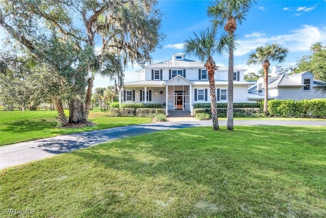 view of front of property featuring a front lawn, covered porch, and metal roof
