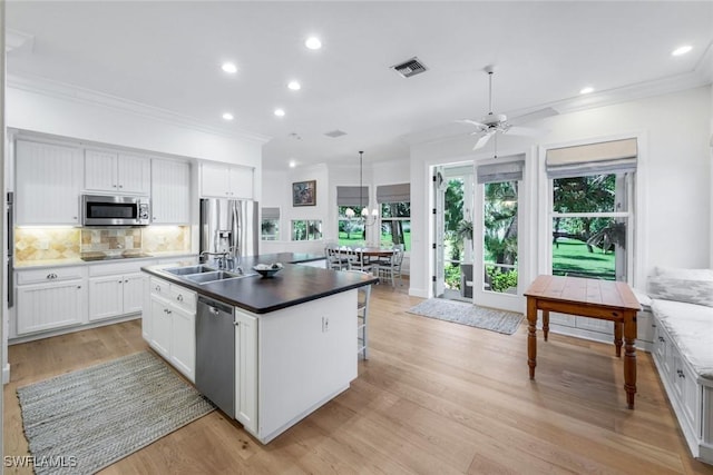 kitchen featuring stainless steel appliances, a sink, visible vents, backsplash, and crown molding
