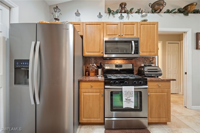 kitchen with light tile patterned floors, decorative backsplash, appliances with stainless steel finishes, and dark stone counters