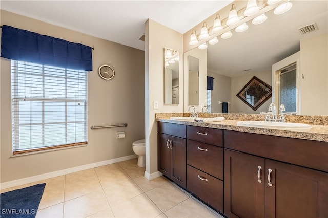 bathroom featuring tile patterned floors, toilet, a sink, visible vents, and double vanity