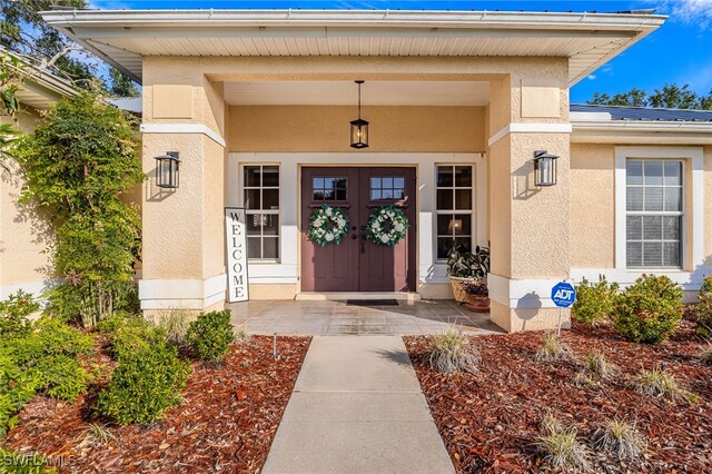 view of exterior entry with stucco siding and covered porch