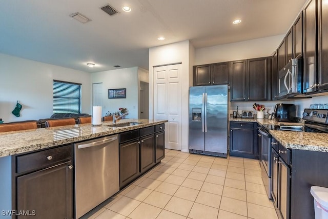 5467 Ferris Ave, Ave Maria, FL 34142 - kitchen with appliances with stainless steel finishes, a sink, light tile patterned flooring, light stone countertops, and dark brown cabinetry
