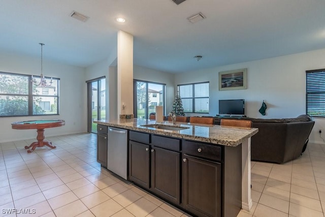 5467 Ferris Ave, Ave Maria, FL 34142 - kitchen with stainless steel dishwasher, a sink, open floor plan, light tile patterned floors, and stone counters