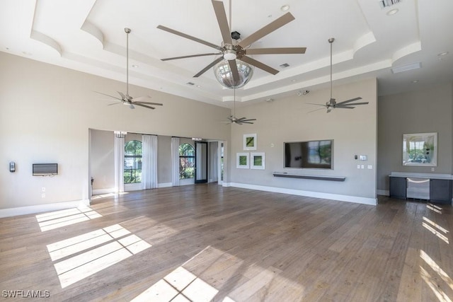 5467 Ferris Ave, Ave Maria, FL 34142 - unfurnished living room featuring a tray ceiling, a towering ceiling, wood finished floors, and baseboards