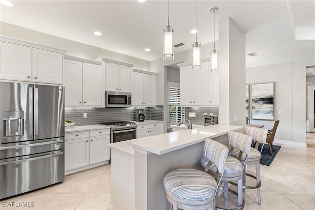 4194 Aspen Chase Dr, Naples, FL 34119 - kitchen featuring stainless steel appliances, tasteful backsplash, light countertops, a kitchen bar, and light tile patterned floors