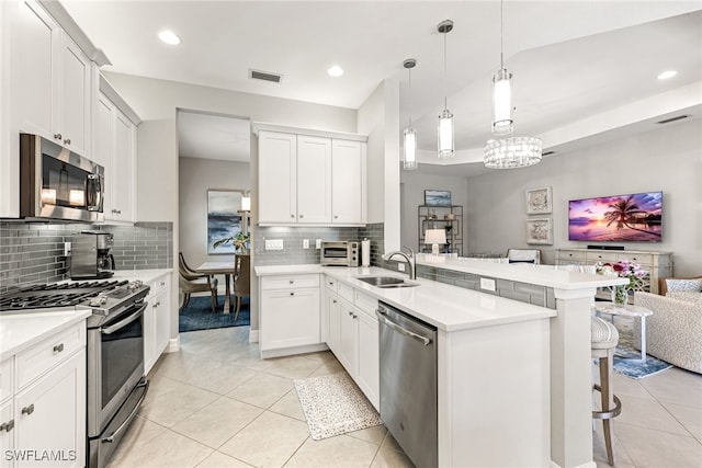 4194 Aspen Chase Dr, Naples, FL 34119 - kitchen with appliances with stainless steel finishes, a peninsula, light tile patterned floors, a kitchen breakfast bar, and recessed lighting