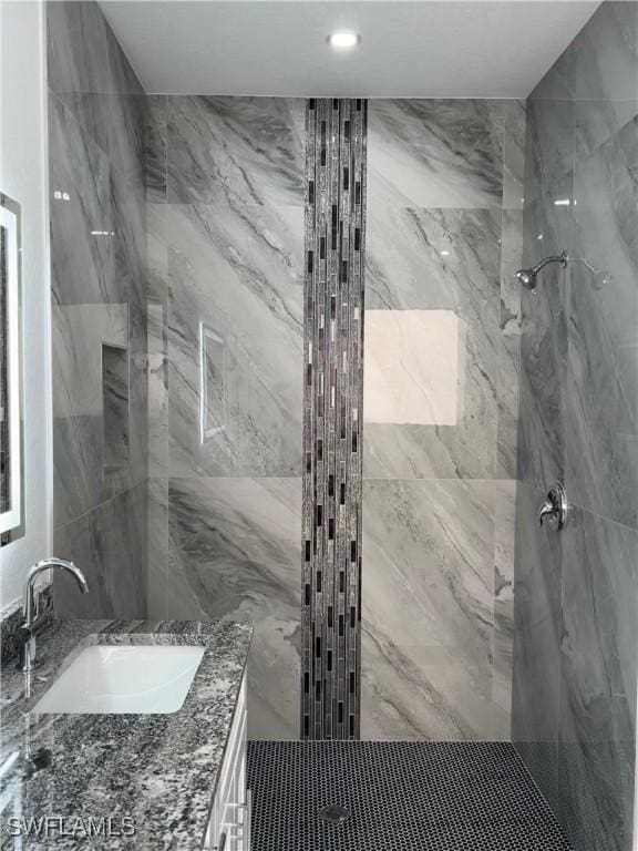 bathroom with vanity and a marble finish shower