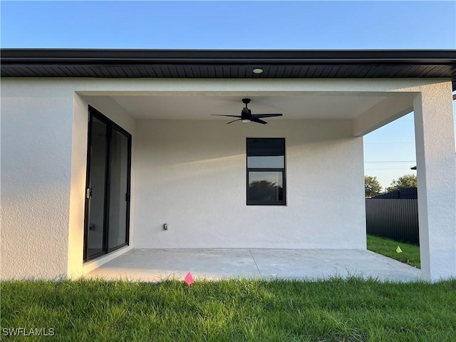 rear view of house with a patio, a ceiling fan, stucco siding, and fence