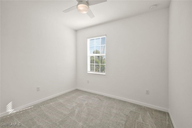 carpeted spare room featuring baseboards and ceiling fan